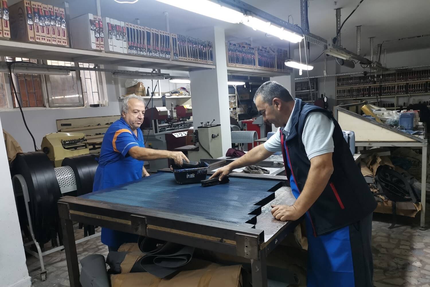 Proces de lucru într-o fabrică de curele din piele, ilustrând prelucrarea manuală a pielii.