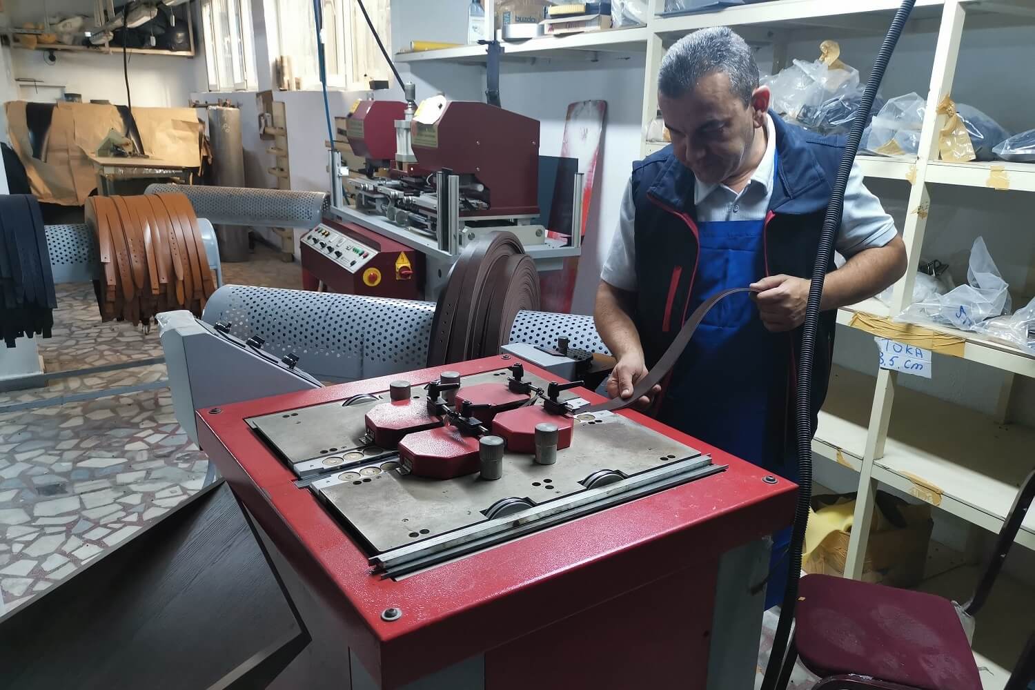 Meșter prelucrează piele naturală într-un atelier de curele realizate manual.