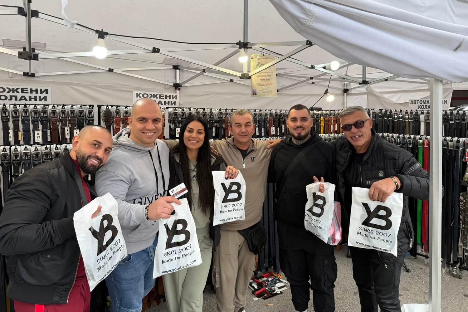 Stand expozițional cu curele din piele lucrate manual, prezentate la un târg.